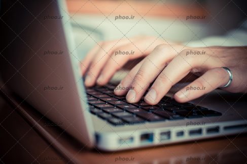 عکس دستان درحال تایپ در لپ تاپ نقره ای