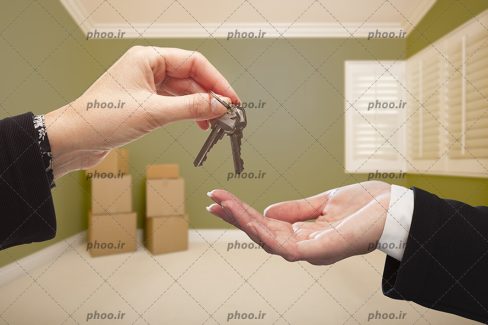 عکس کلید در دست درحال تحویل دادن به دیگری در خانه