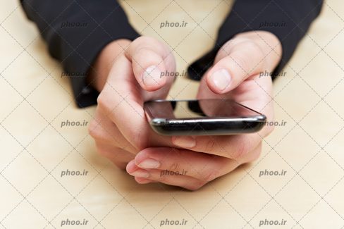 عکس گوشی در دست روی میز