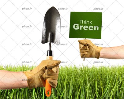 عکس دست هایی با بیلچه باغبانی و یک تابلو سبز با نوشته انگلیسی (think green) در بالای چمن های سبز در پس زمینه سفید