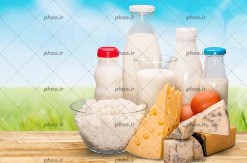 عکس محصولات لبنی روی میز چوبی در پس زمینه چمن سبز و آسمان آبی