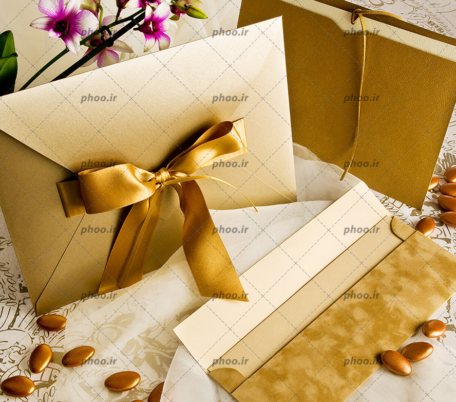 عکس با کیفیت چند مدل کارت عروسی تزئین شده در کنار دانه های طلایی و شاخه گل