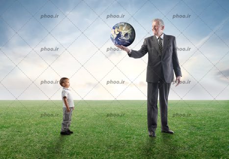 عکس با کیفیت مرد مسن با کره ی زمین روی دست در مقابل پسر بچه روی زمین سر سبز