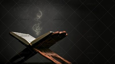 عکس با کیفیت قرآن بر روی رحل چوبی و نور زرد بیرون آمده از آن در زمینه مشکی