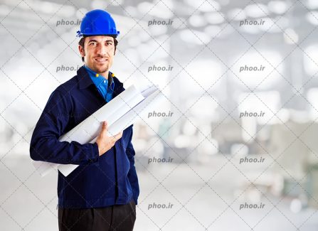عکس مهندس ساختمان با کلاه ایمنی و نقشه های ساختمانی در دست