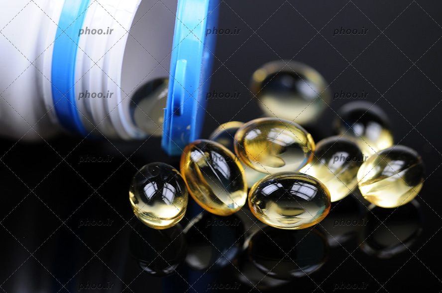 عکس قوطی قرص و قرص های ویتامین دی ریخته شده روی زمین