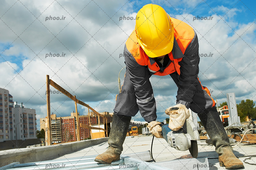 عکس یک کارگر با کلاه ایمنی و لباس کار در حال برش زدن یک فلز با دستگاه فرز