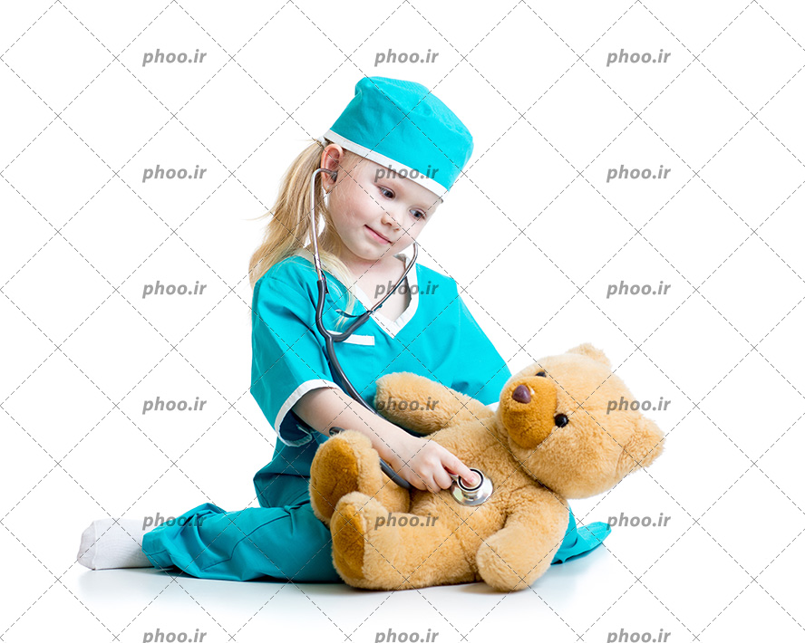 عکس دختر بچه با لباس و گوشی پزشکی در حال معاینه عروسک خرسی در پس زمینه سفید