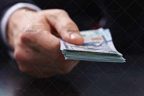 عکس مقداری پول در دست انسان از نمای نزدیک