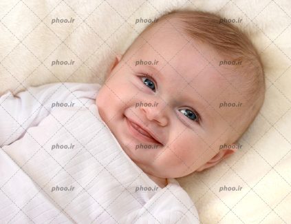 عکس با کیفیت نوزاد زیبا با چشم های سبز و لبخند روی پتوی سبز
